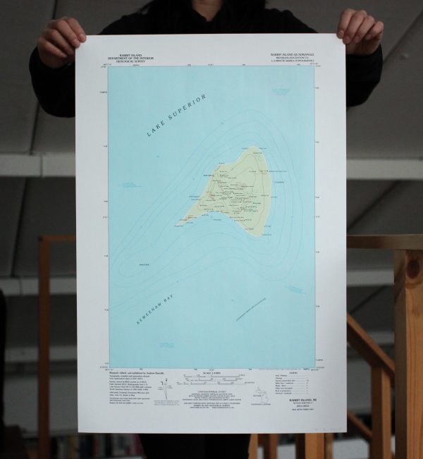 Two hands holding a large topographic map artwork designed in the classic USGS style.